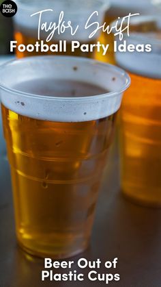 two plastic cups filled with beer sitting on top of a table