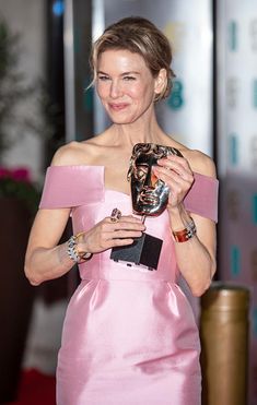 a woman in a pink dress holding an award