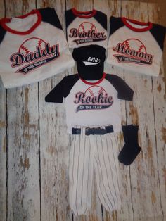 three baseball uniforms are laid out on a wooden surface, one is white and the other is black