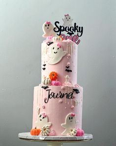 a three tiered cake with ghost decorations on top and spooky one written on the side