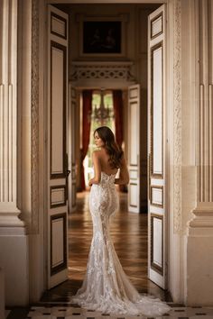 a woman is standing in an open doorway wearing a wedding dress and looking at the camera