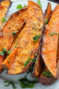 baked sweet potato wedges on a plate with parsley sprinkled on top