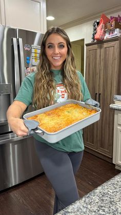 a woman holding a pan of food in her kitchen