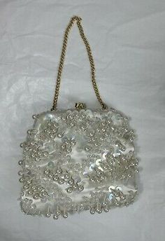 a white purse with pearls hanging from it's chain on a white sheeted surface