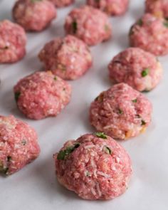 raw meatballs are lined up on a white surface