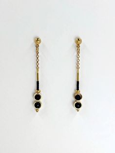 These earrings are dainty and minimalistic but detailed! Thick, straight cut, golden brass rings encircle each semi precious stone of matte black onyx, complimentary tiny, matte black glass seed beads sit above.  The shiny warm, golden brass contrasts beautifully with the deep black stone.  The simplicity and geometric shapes create a contemporary design.  A solid brass ball stud with stainless steel earring post sits at the top.  Approximate measurements- 5.5 cms long 0.75 cm wide All Set Theor Minimalist Gold Plated Earrings, Black Dainty Metal Jewelry, Dainty Black Metal Jewelry, Minimalist Matte Gold Metal Jewelry, Minimalist Gold Plated Linear Earrings With Adjustable Chain, 14k Gold-filled Drop Earrings With Adjustable Chain, 14k Gold Filled Drop Earrings With Adjustable Chain, Minimalist 14k Gold Linear Earrings With Adjustable Chain, Minimalist Black Pierced Jewelry