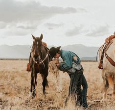 a man standing next to two horses in a field