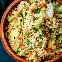 a wooden bowl filled with rice and green onions