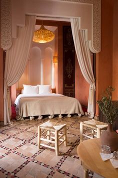 a bed sitting in a bedroom next to a table with chairs and a vase on top of it