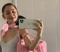 a woman taking a selfie in front of a mirror wearing a pink scarf and holding a cell phone