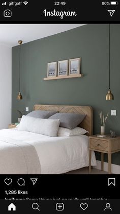 a bedroom with green walls and white bedding, two framed pictures on the wall