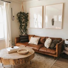 a living room with leather couches and two pictures on the wall above them, along with a coffee table