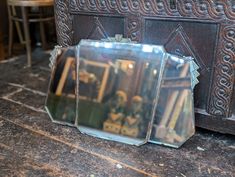 two mirrors sitting on top of a wooden floor next to a table with chairs in it