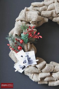 a burlock wreath with red berries and greenery on it is hung on a black wall