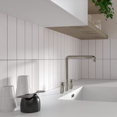 a white kitchen with black and white accessories on the counter top next to a potted plant