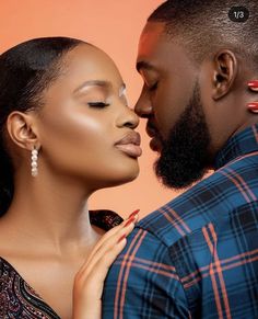 a man and woman kissing each other in front of an orange background