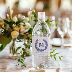 a bottle of water sitting on top of a table next to flowers and wine glasses