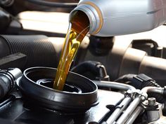 a person pouring oil into a car engine