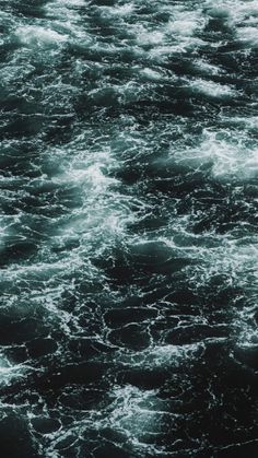 the water is very dark and choppy with little waves coming in to shore, as seen from above