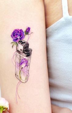 a woman's arm with purple flowers in a jar tattoo on the left side of her arm