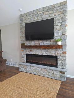 a living room with a large stone fireplace and flat screen tv mounted on the wall