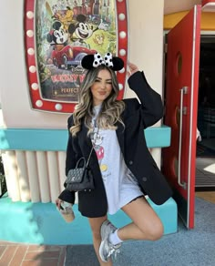 a woman posing in front of a mickey mouse sign