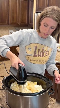 a woman is mixing potatoes in a large pot