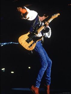 a man with a guitar on stage in the middle of his legs, and one hand holding an electric guitar