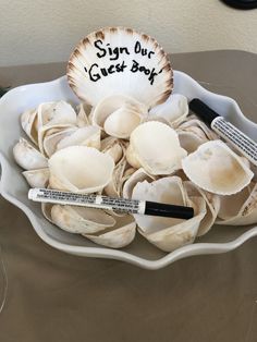 a bowl filled with lots of clams on top of a table next to marker markers