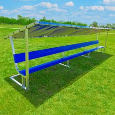 a blue bench sitting in the middle of a grass covered field with an awning over it