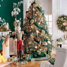 a christmas tree decorated with gold and green ribbons, ornaments and decorations in a living room