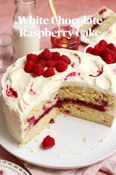 a white chocolate raspberry cake on a plate with a slice missing from it