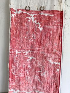 an old red and white cloth hanging on a wall