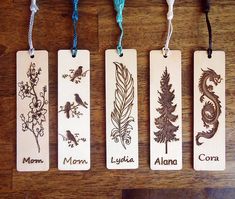 four wooden bookmarks with different types of plants and animals on them hanging from cords