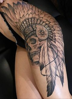 a woman's thigh with a skull and feather headdress tattoo on it