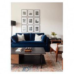 a living room with blue couches and pictures on the wall above it, along with two chairs