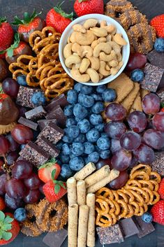 a platter filled with fruit, crackers and pretzels next to chocolate covered strawberries