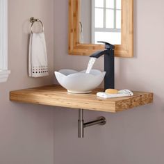 a bathroom sink sitting under a mirror on top of a wooden counter next to a towel rack