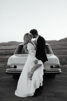 a man and woman kissing in front of a car