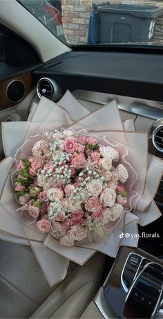 a bouquet of pink and white flowers sitting in the center of a car's dashboard