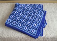 two blue crocheted squares sitting on top of a white rug