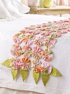 a white bed topped with lots of pink and green flowers