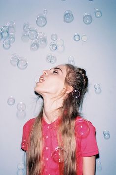 a woman blowing bubbles in the air with her eyes wide open and mouth wide open