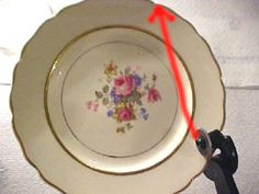 a white plate with flowers painted on it and a red arrow pointing to the center