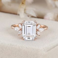 an emerald cut engagement ring with three diamonds on the band and side stones around the band