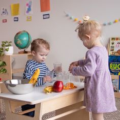 two young children are playing with food in a play room at home or school,