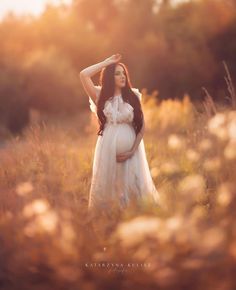 a pregnant woman standing in a field with her hands on her head