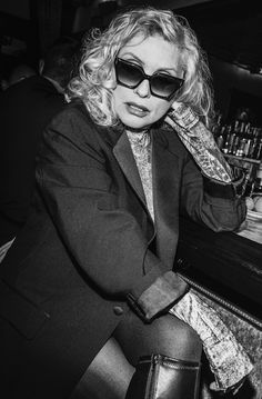 a woman sitting at a bar wearing sunglasses