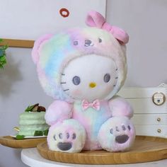 a hello kitty stuffed animal sitting on top of a wooden table next to a cake