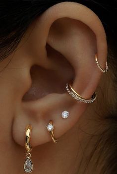 three different types of ear piercings on a woman's ear with diamonds in the middle